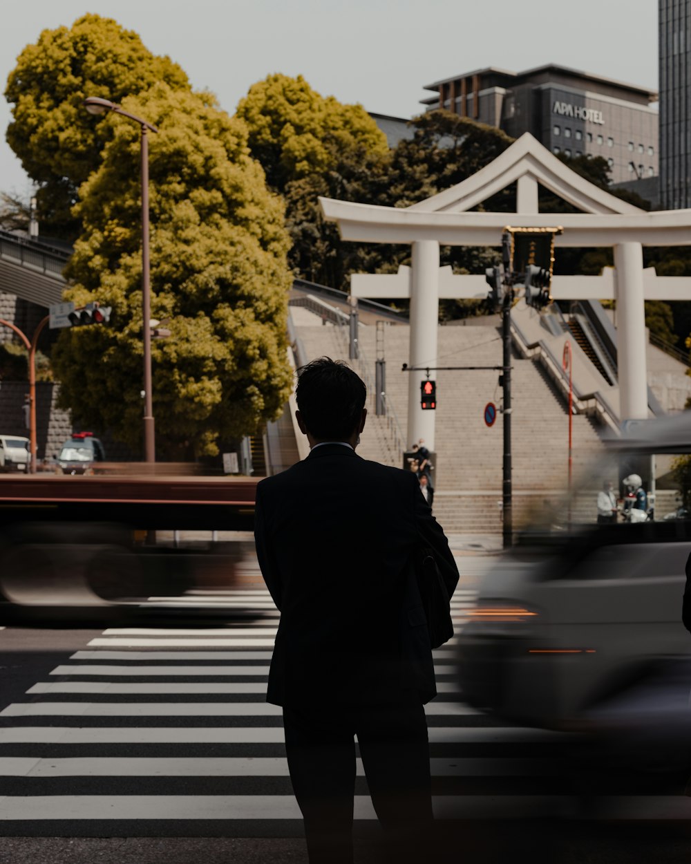 a man in a suit standing at a crosswalk