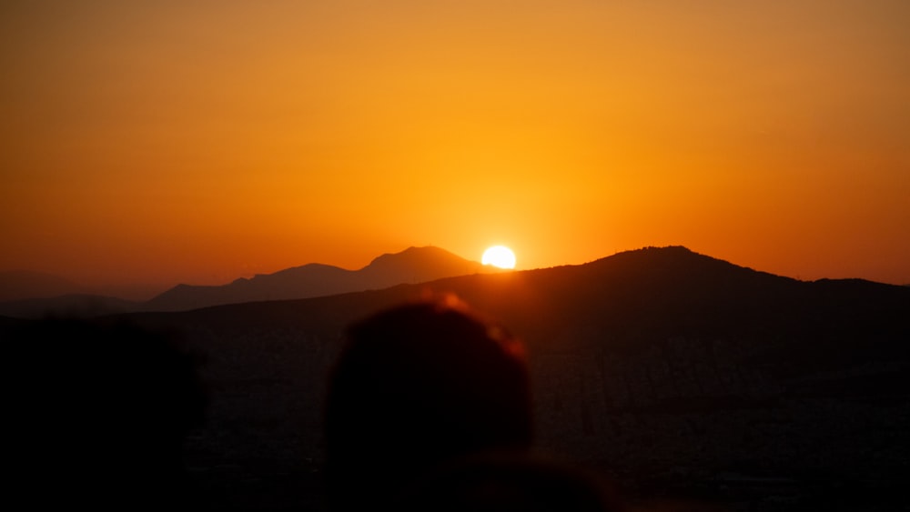 the sun is setting over a mountain range