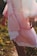 A woman wearing a soft pink dress in a serene outdoor setting.