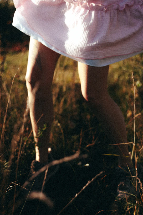 Woman in pink summer dress walking through field in hot weather