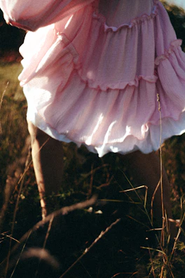 Soft focus shot of a flowing pastel dress moving gracefully in the breeze outdoors.