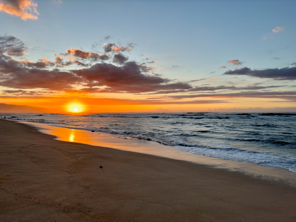 the sun is setting over the ocean on the beach