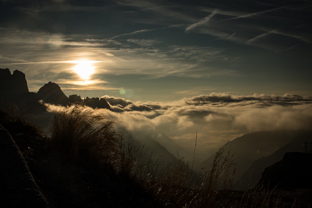 the sun is shining through the clouds over the mountains