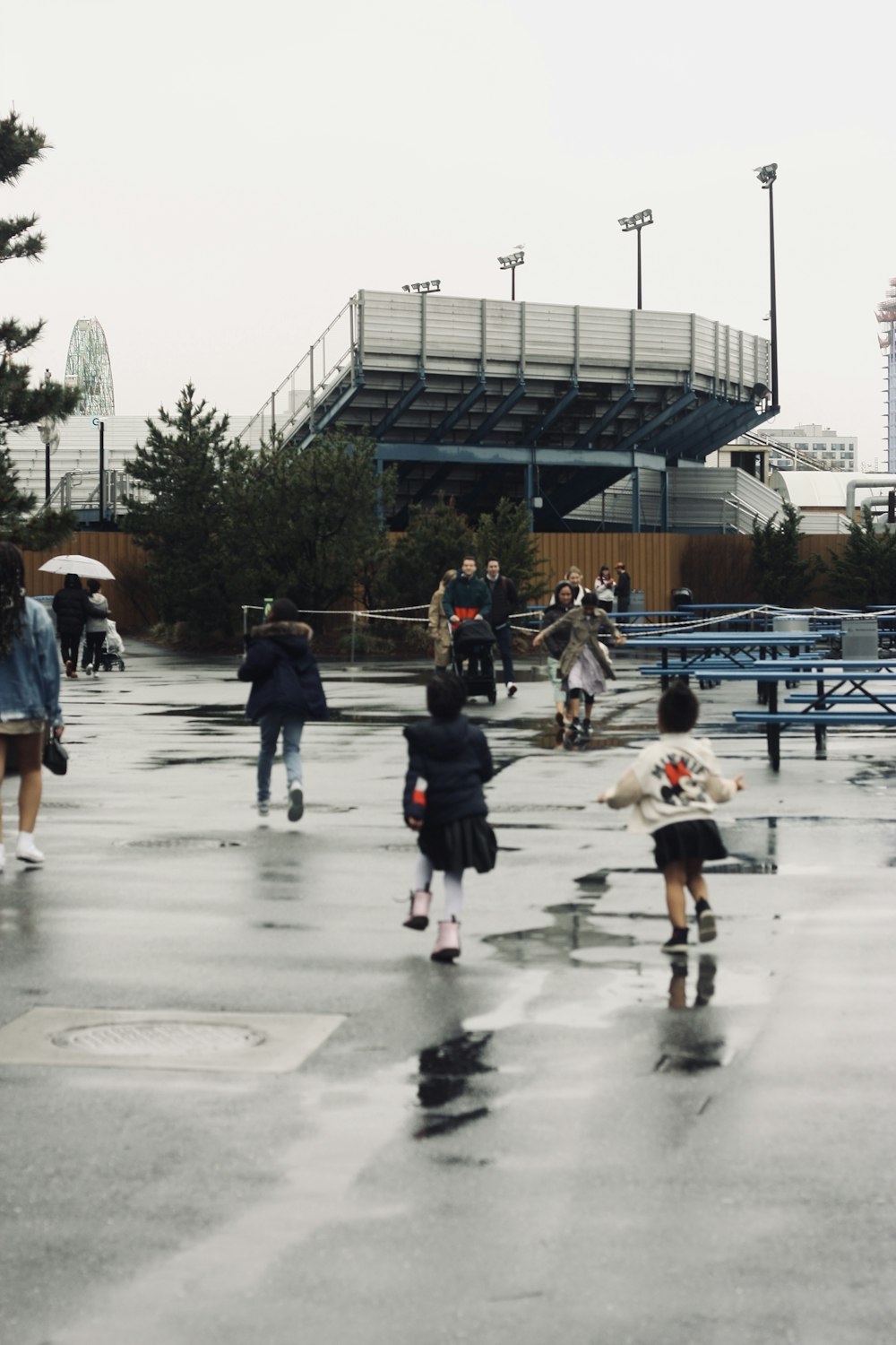a group of people walking across a wet parking lot