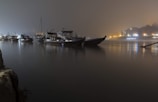 Nighttime shot of boats lit by lanterns floating on a peaceful river.
