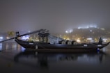A warmly lit traditional dhow boat gliding past Dubai's illuminated skyline at night.