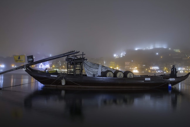 A warmly lit traditional dhow boat gliding past Dubai's illuminated skyline at night.