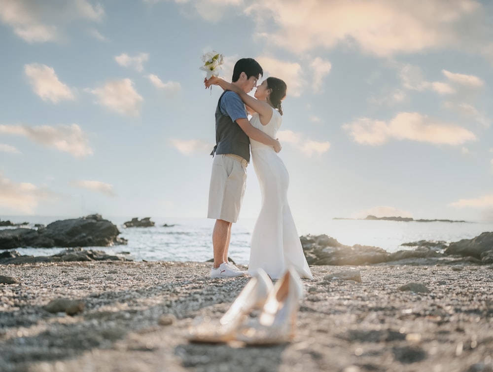 a man and a woman standing on a beach next to the ocean