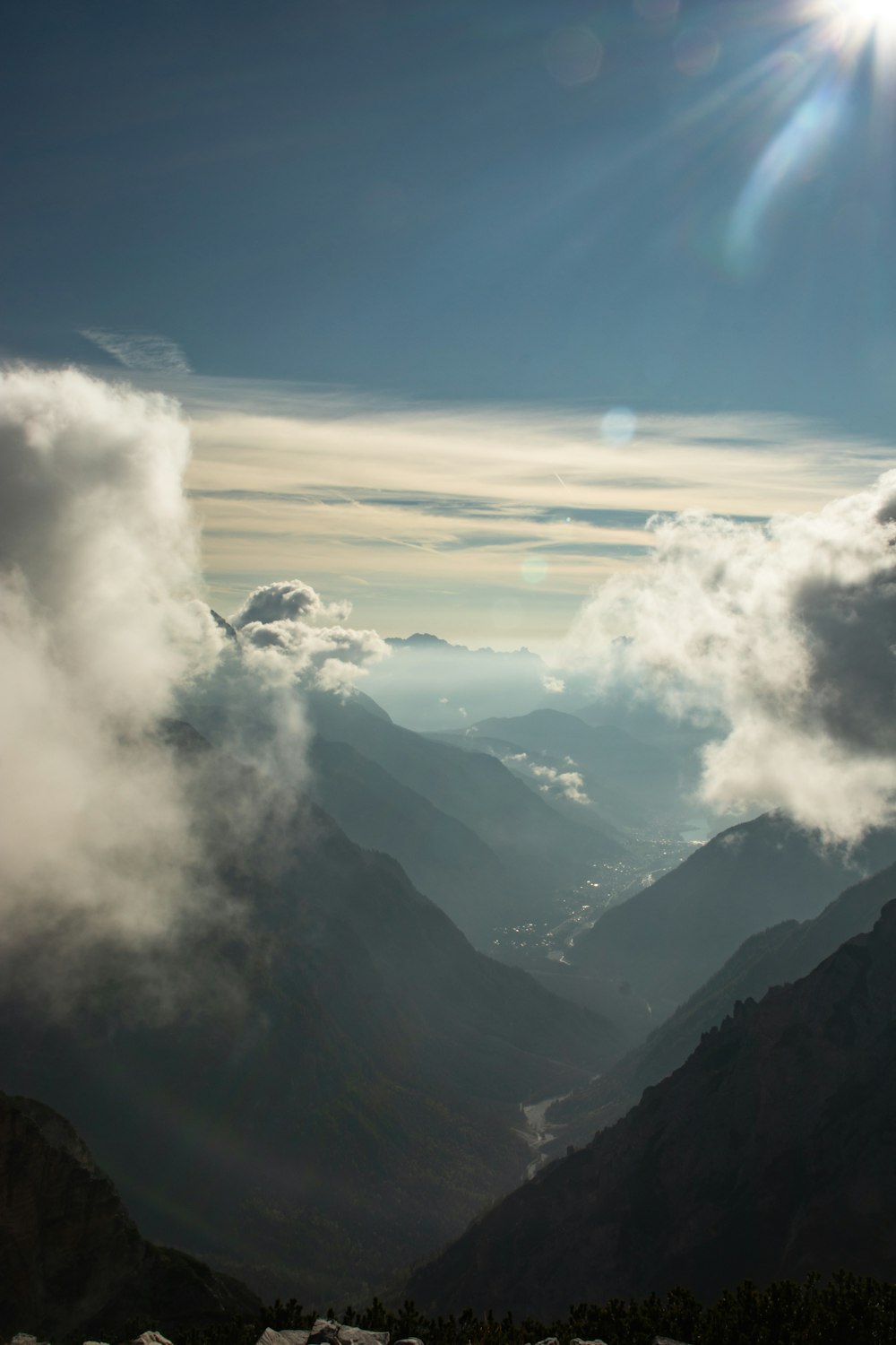 the sun is shining over the mountains and clouds