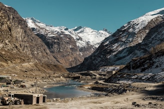 Engineers surveying a remote Himalayan road construction site surrounded by snowy peaks.