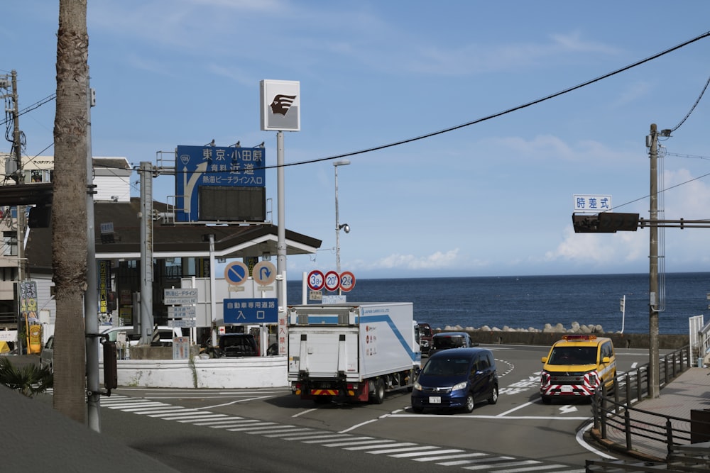 a couple of trucks driving down a street next to the ocean