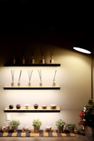 A minimalist display of small scents' products on a light, neutral-toned shelf with natural sunlight.