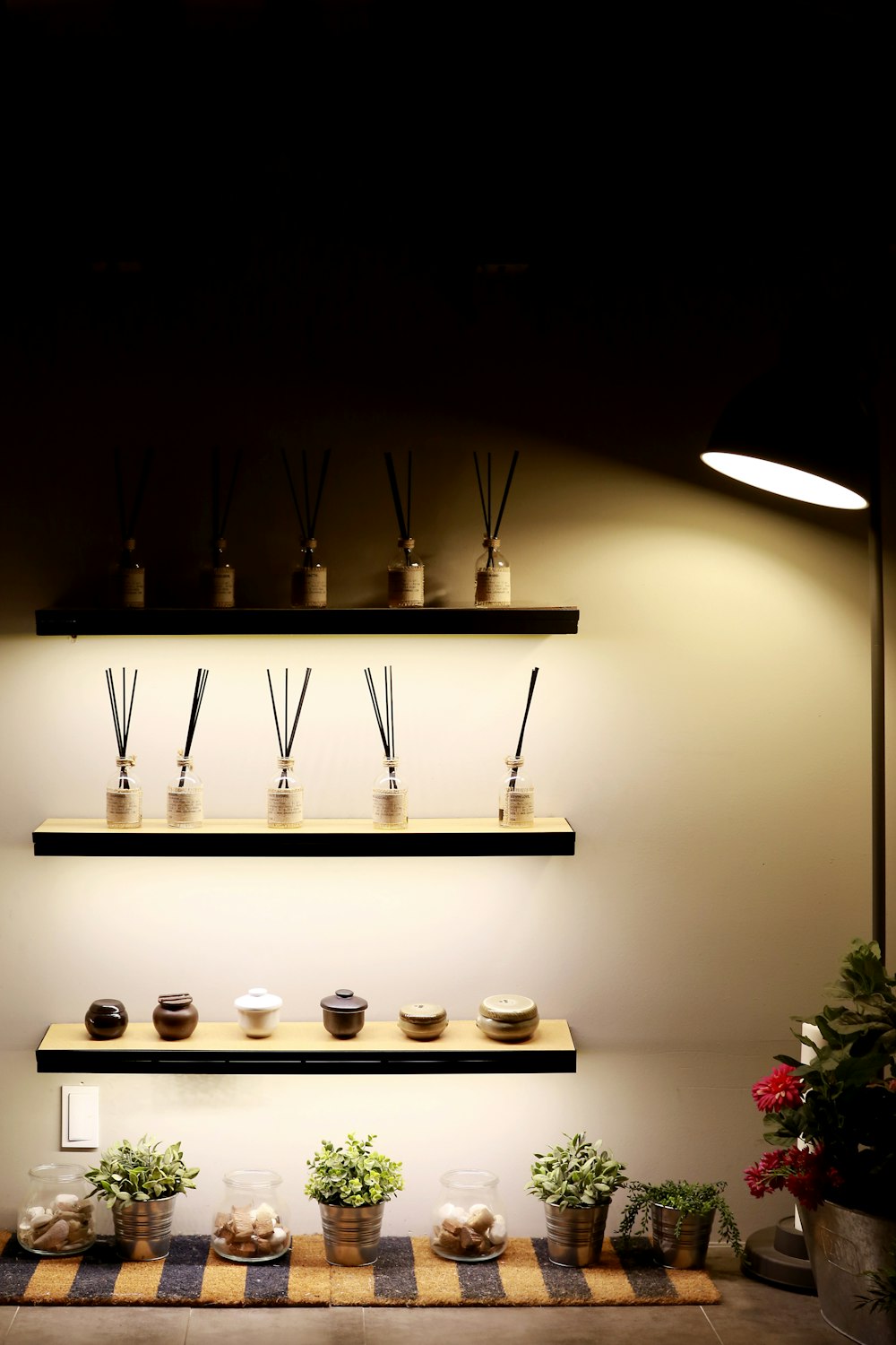 a shelf with candles and plants on it