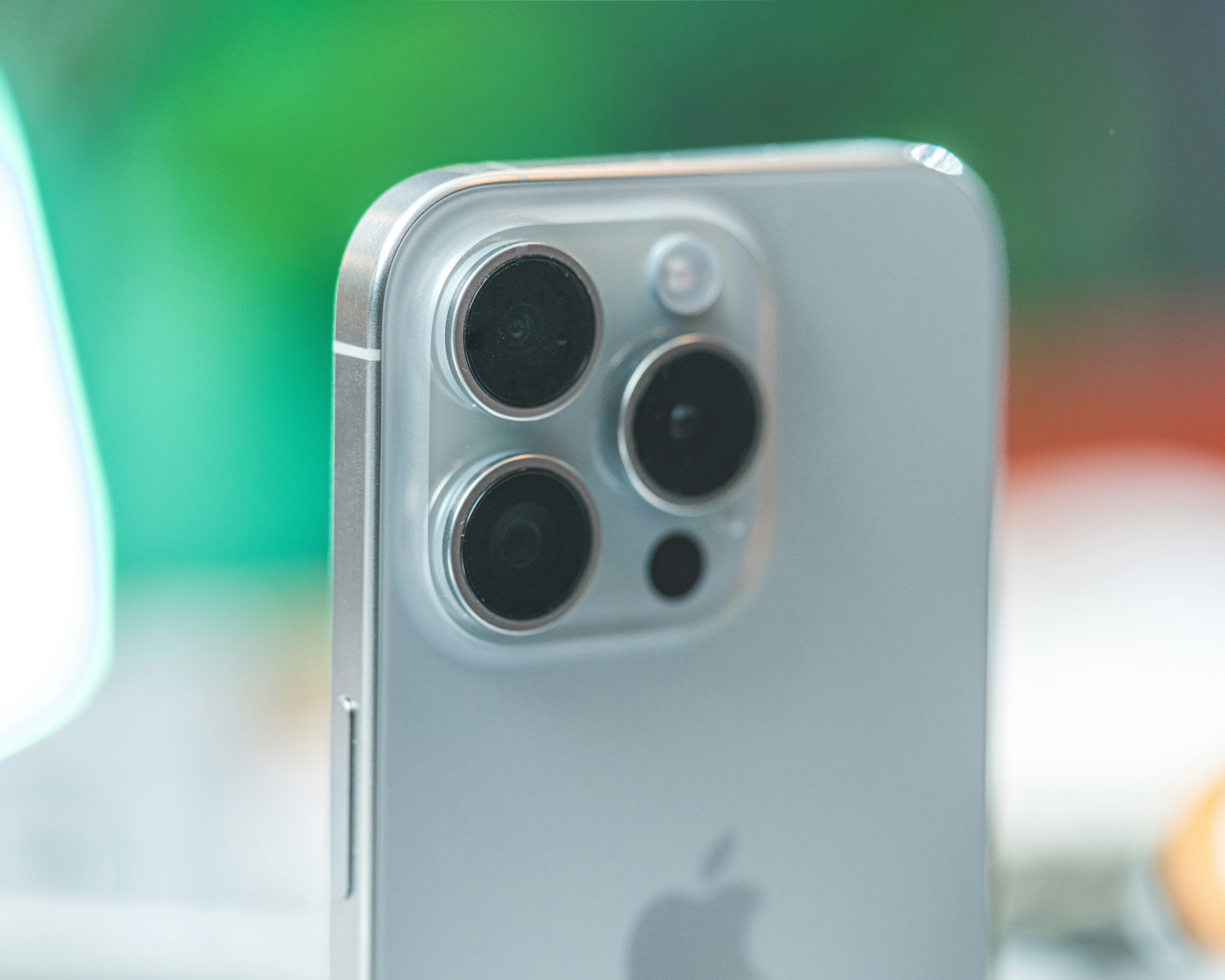 Close-up of iPhone camera system with blurred warm-toned background, professional photography feel, dim atmospheric