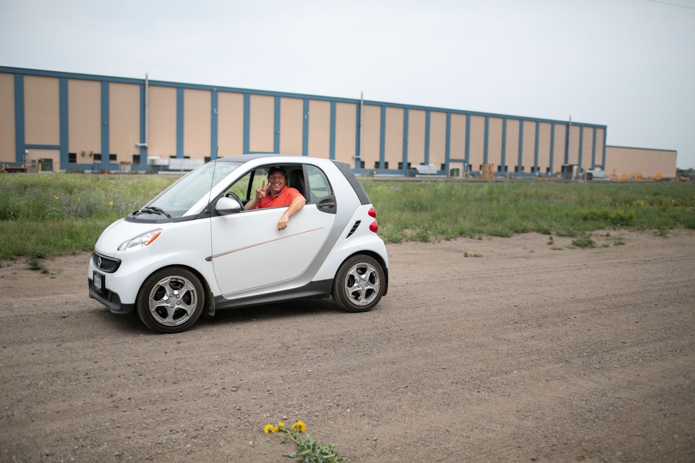 a woman sitting in a small car on a dirt road