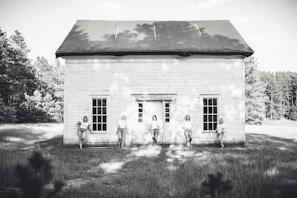 Black and white portrait of the band members standing against a rustic wooden fence