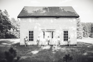 Black and white portrait of the band members standing against a rustic wooden fence
