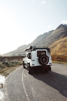 A rugged SUV navigating a winding mountain road under clear skies.