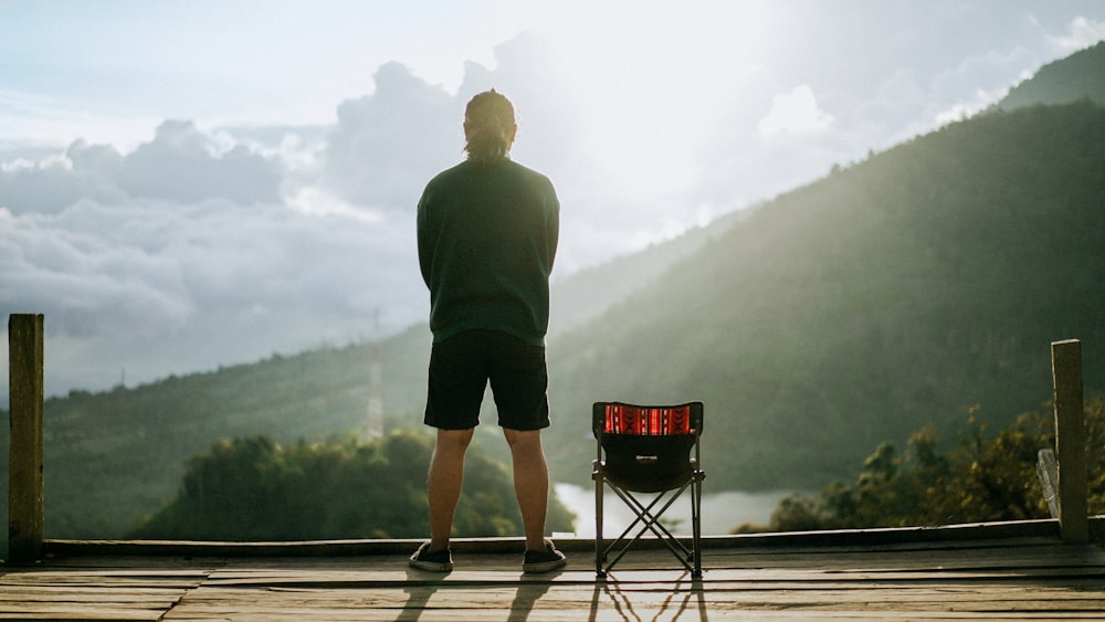 a man standing on a wooden deck next to a chair