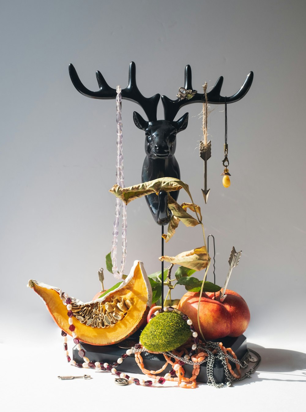 a sculpture of a deer head, fruit, and beads