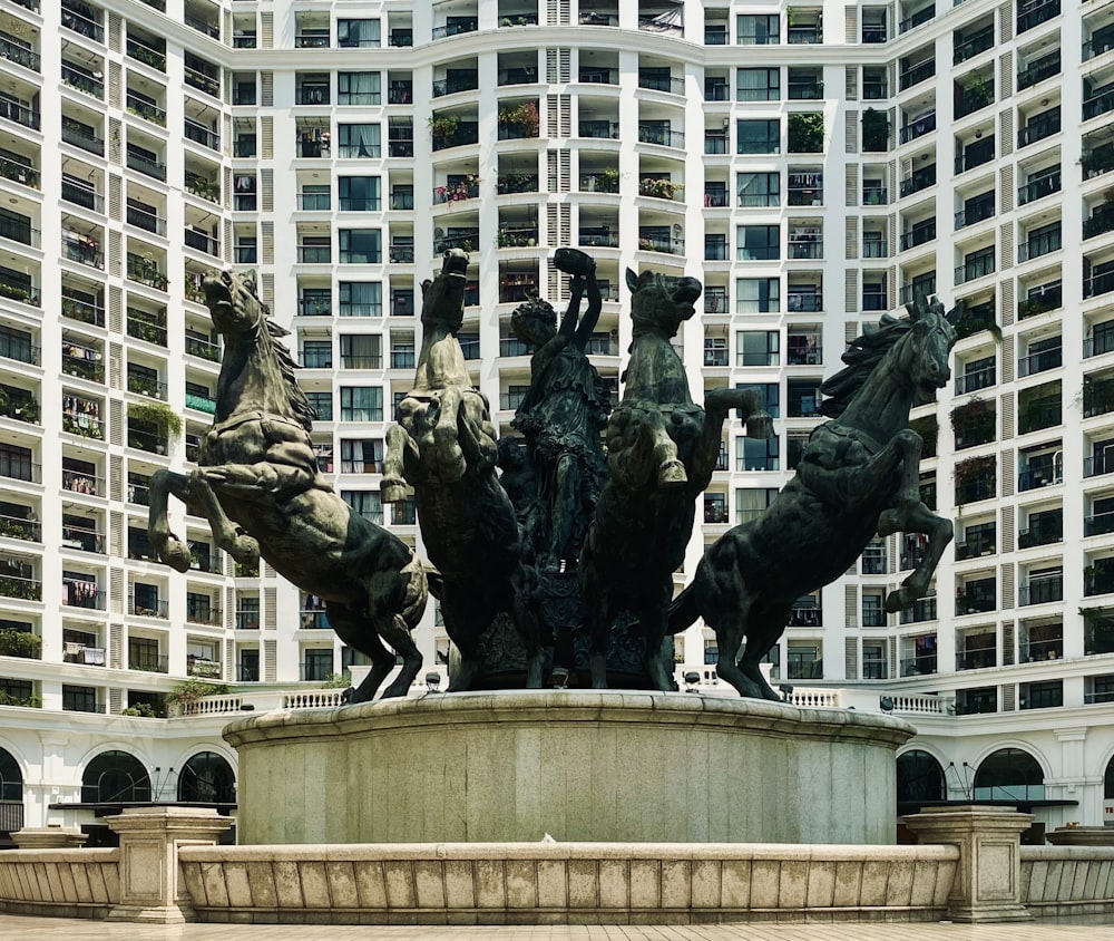 a statue of a group of horses in front of a building
