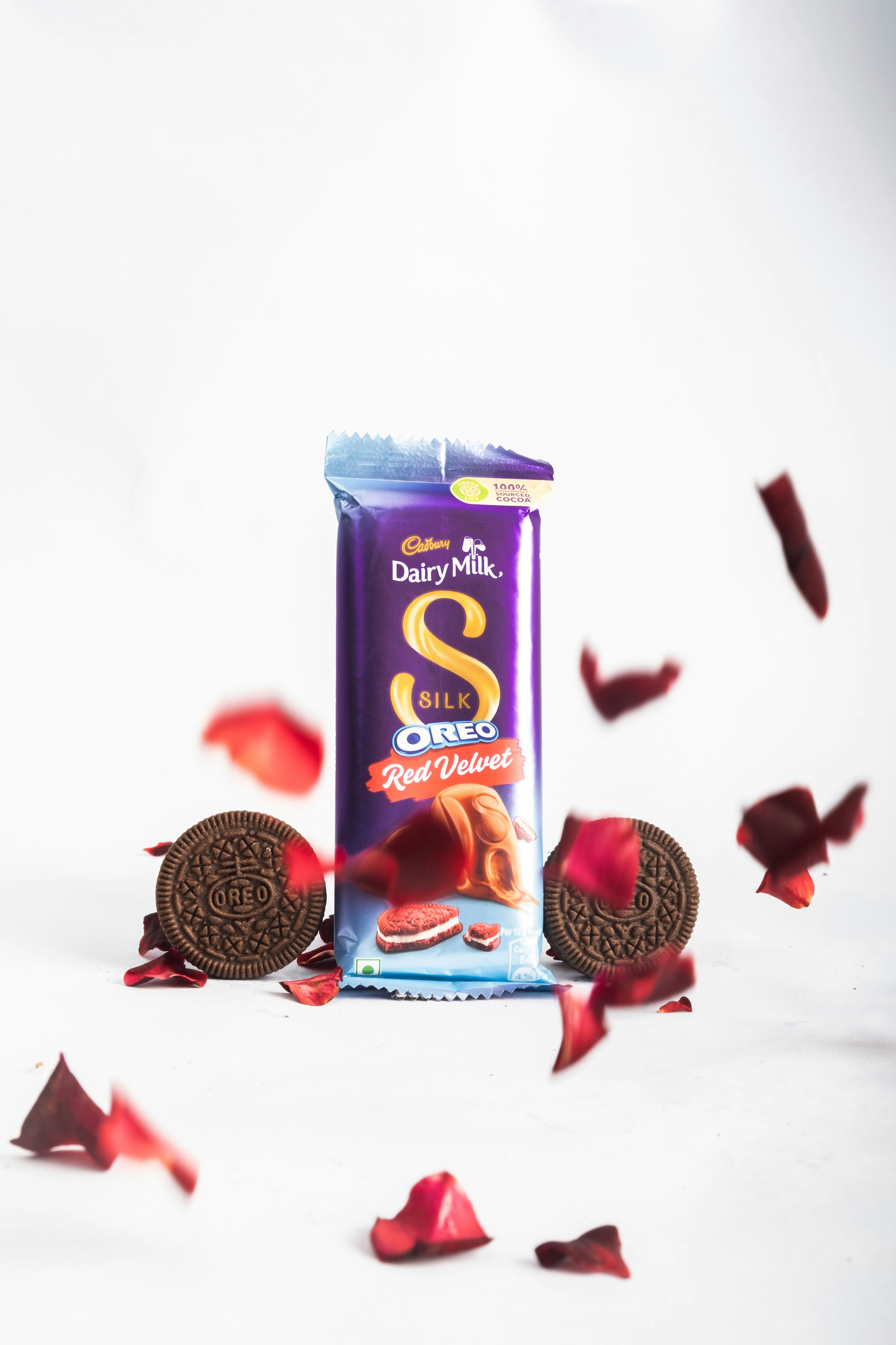 an oreo cookie and rose petals on a white background