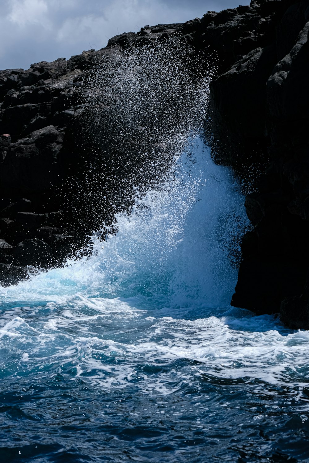 a large wave crashing into a rocky shore