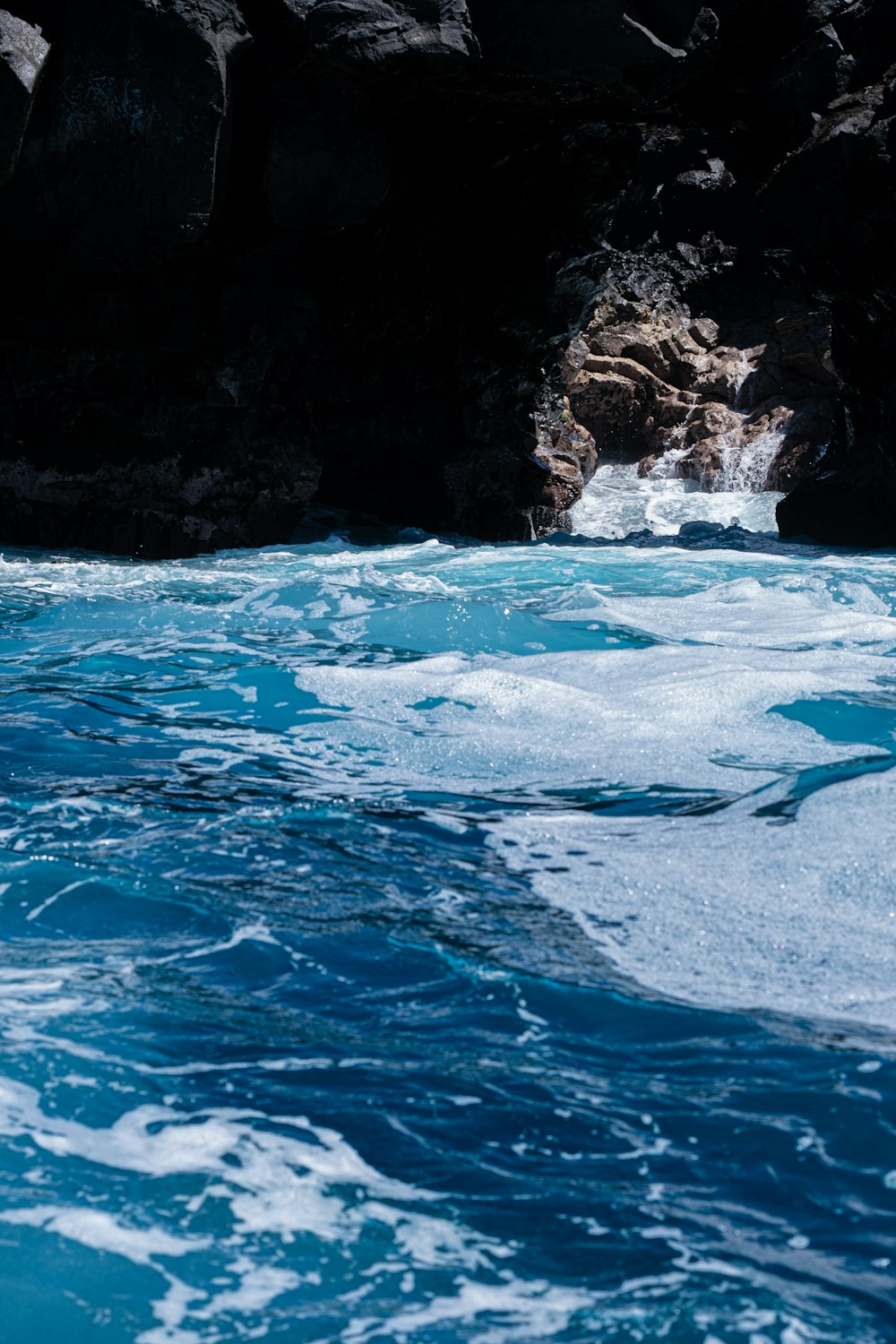 a body of water with a cave in the background