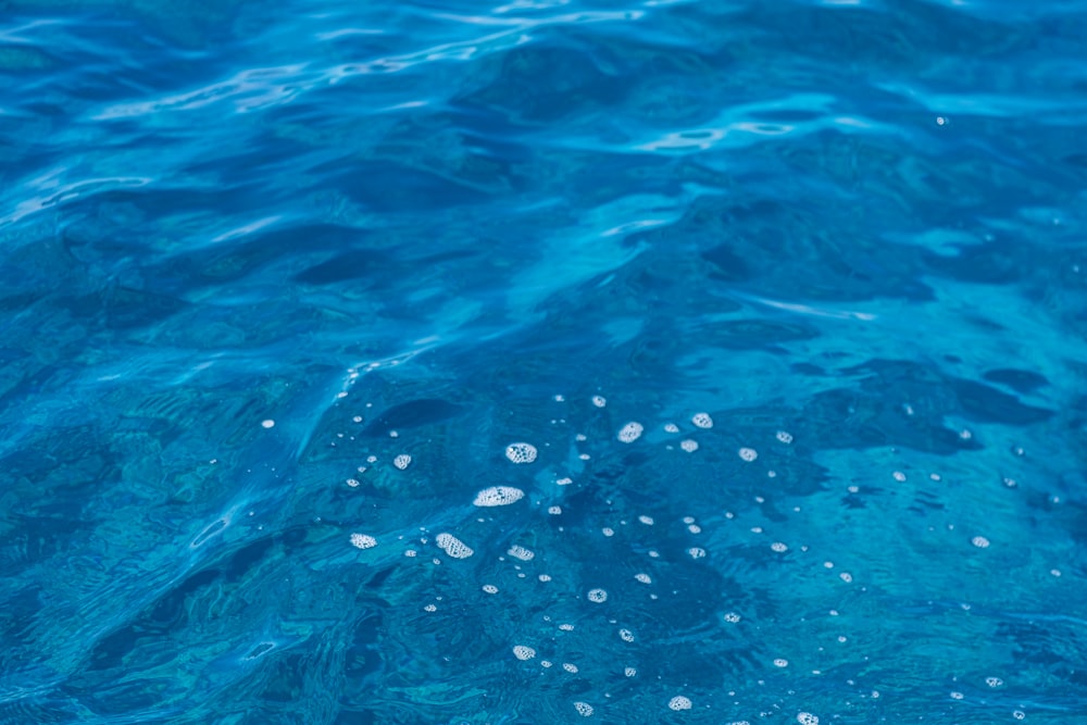a close up of a blue water surface with bubbles