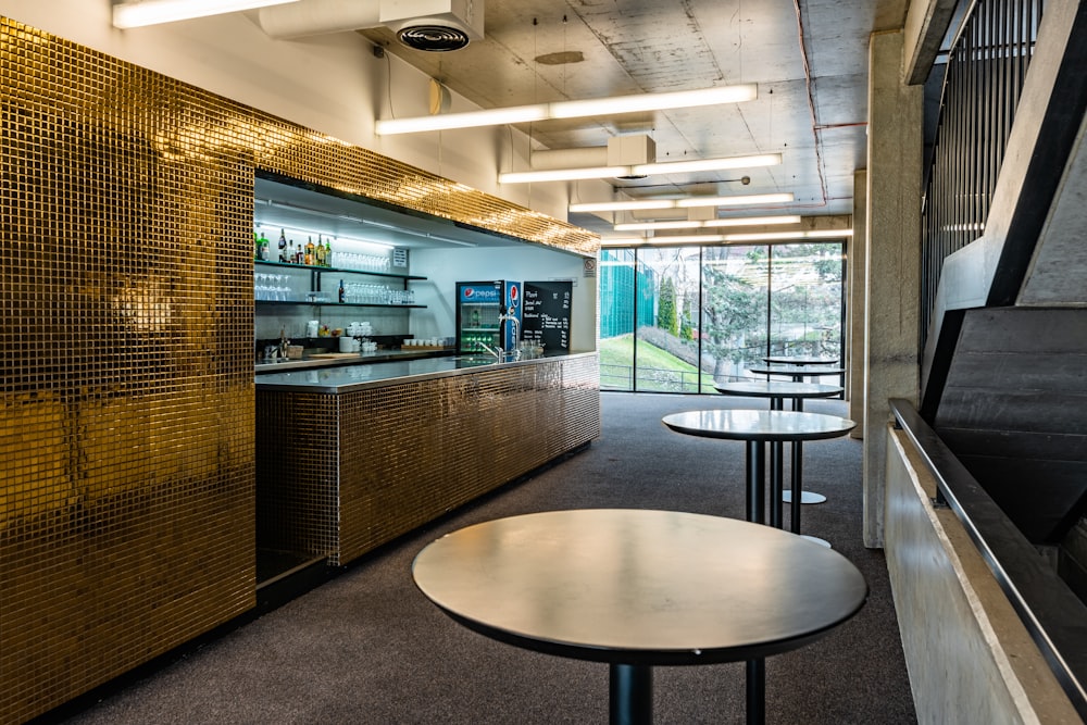 a room with a counter, chairs, and tables in it