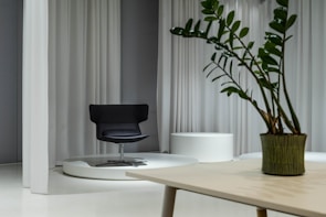 A sleek black swivel chair positioned beside a minimalist wooden desk.