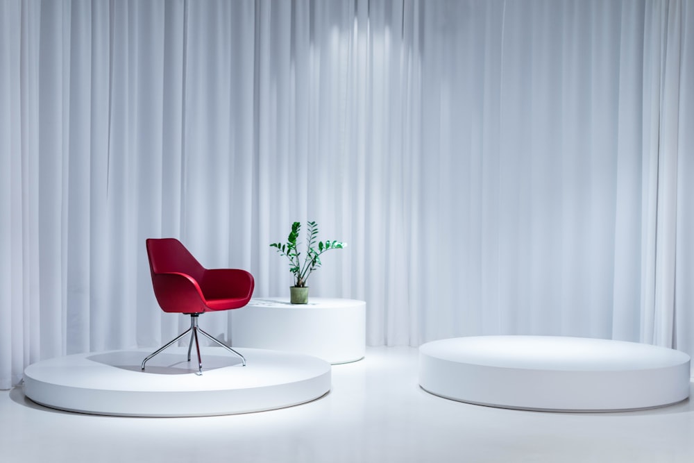 a white room with a red chair and a round table