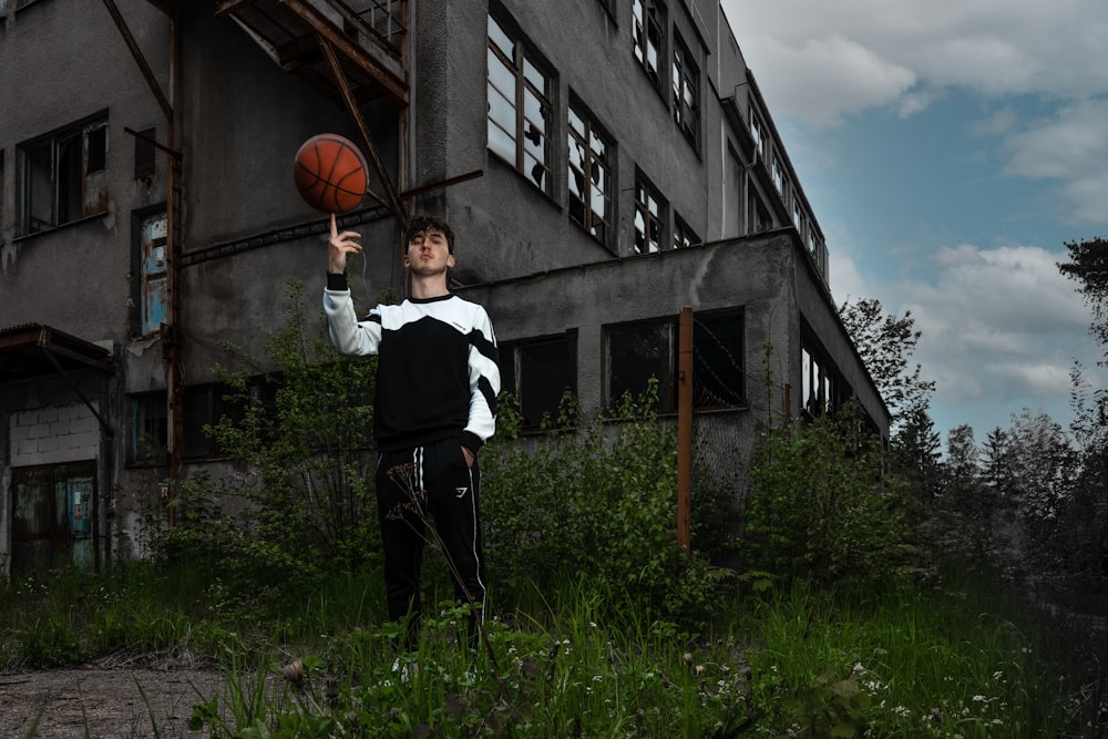 a man holding a basketball in front of a building