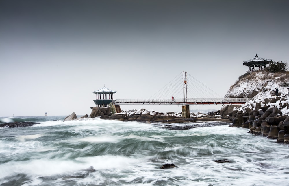 a bridge over a body of water next to a rocky shore