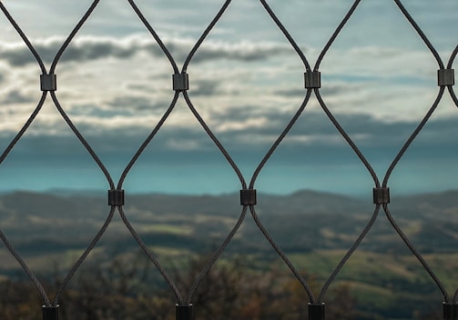 A sprawling farm fenced with wire mesh, with hills in the background.