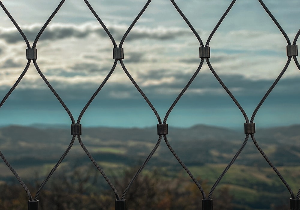 a close up of a fence with mountains in the background
