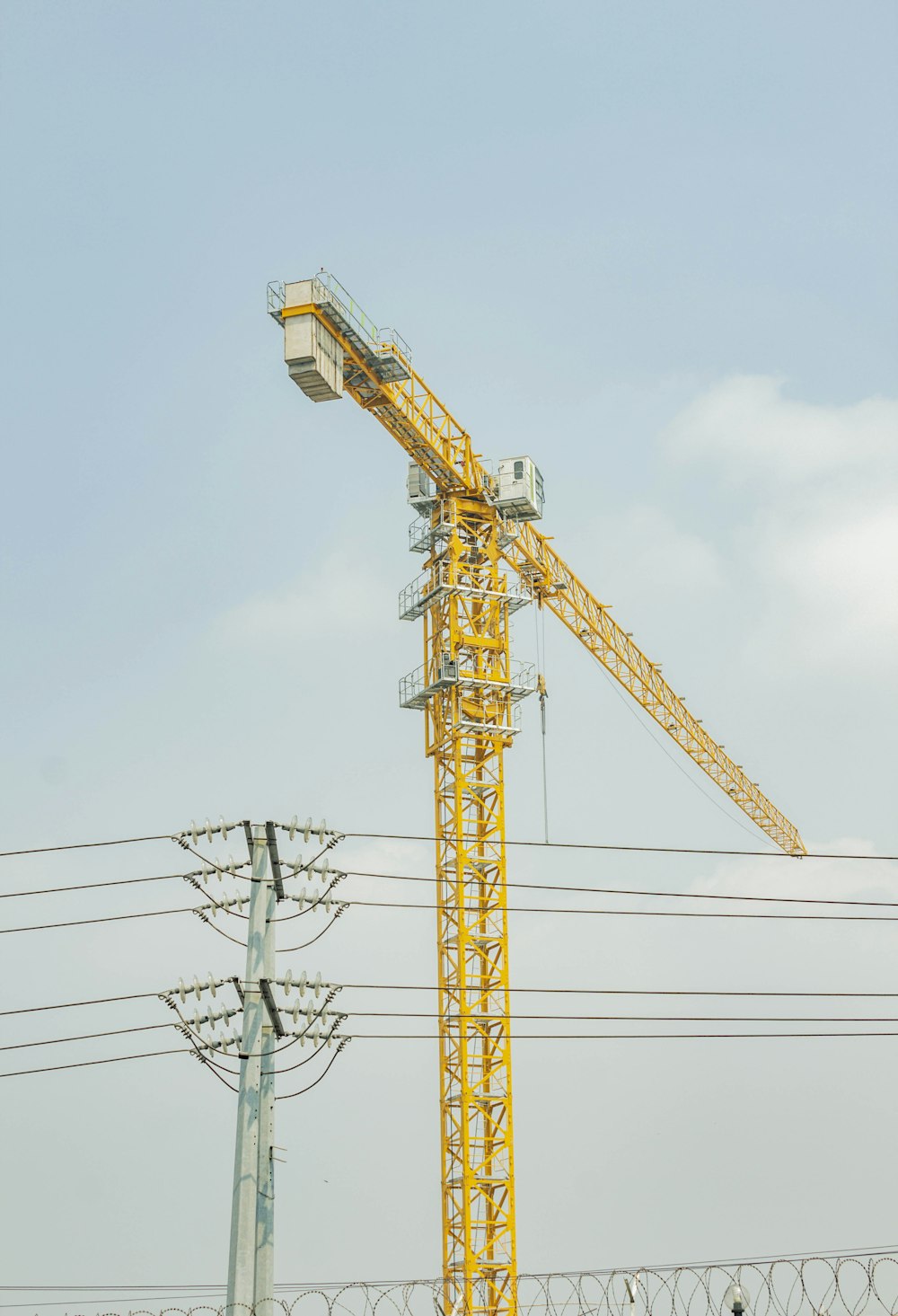 a yellow crane sitting on top of a metal pole