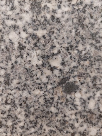 Close-up of a skilled inspector examining a polished granite slab under bright lighting.