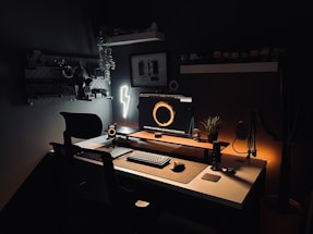 a desk with a computer, keyboard, mouse and light
