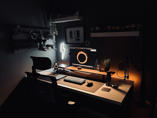 a desk with a computer, keyboard, mouse and light