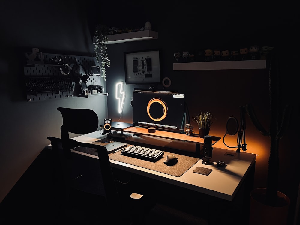 a desk with a computer, keyboard, mouse and light