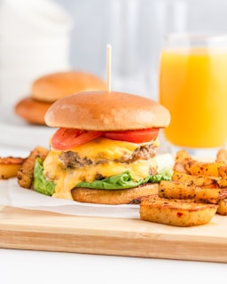 a cheeseburger with fries and a glass of orange juice