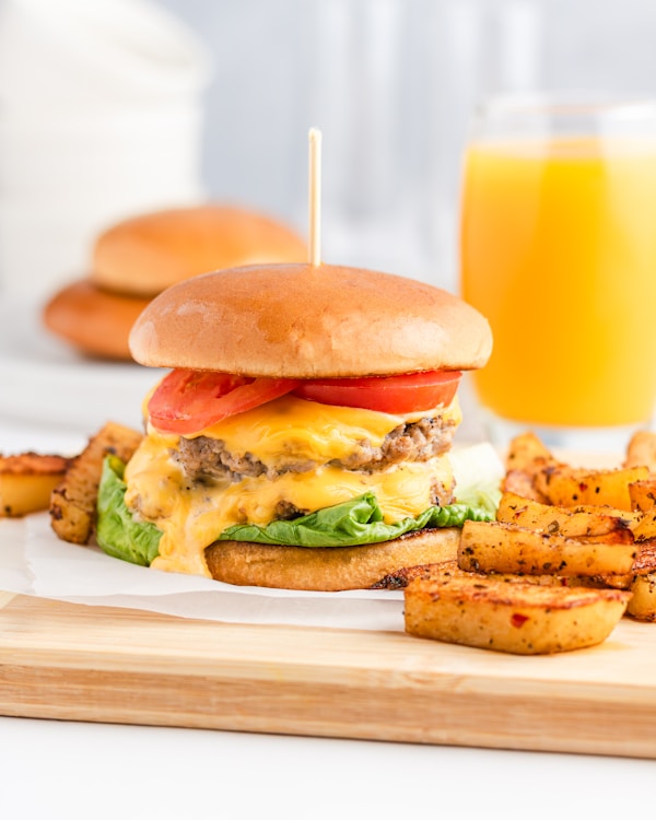 A cheeseburger with fries and a glass of orange juice