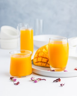 two glasses of orange juice on a plate