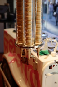 Stacks of ice cream cones are neatly arranged in a transparent vertical holder attached to an ice cream cart with tastefully designed graphics and branding.