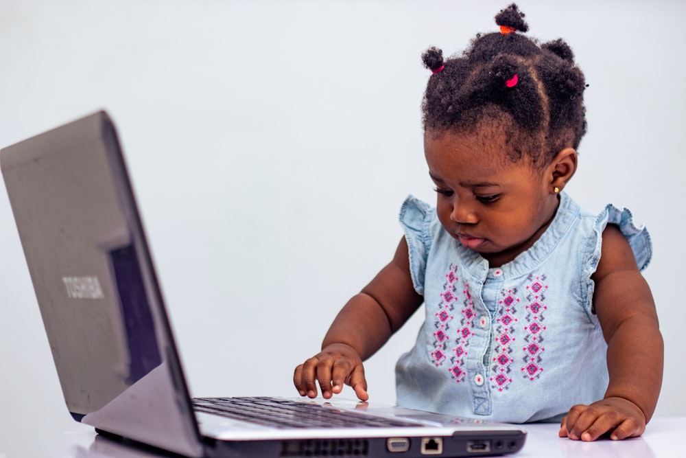 a little girl playing with a laptop computer