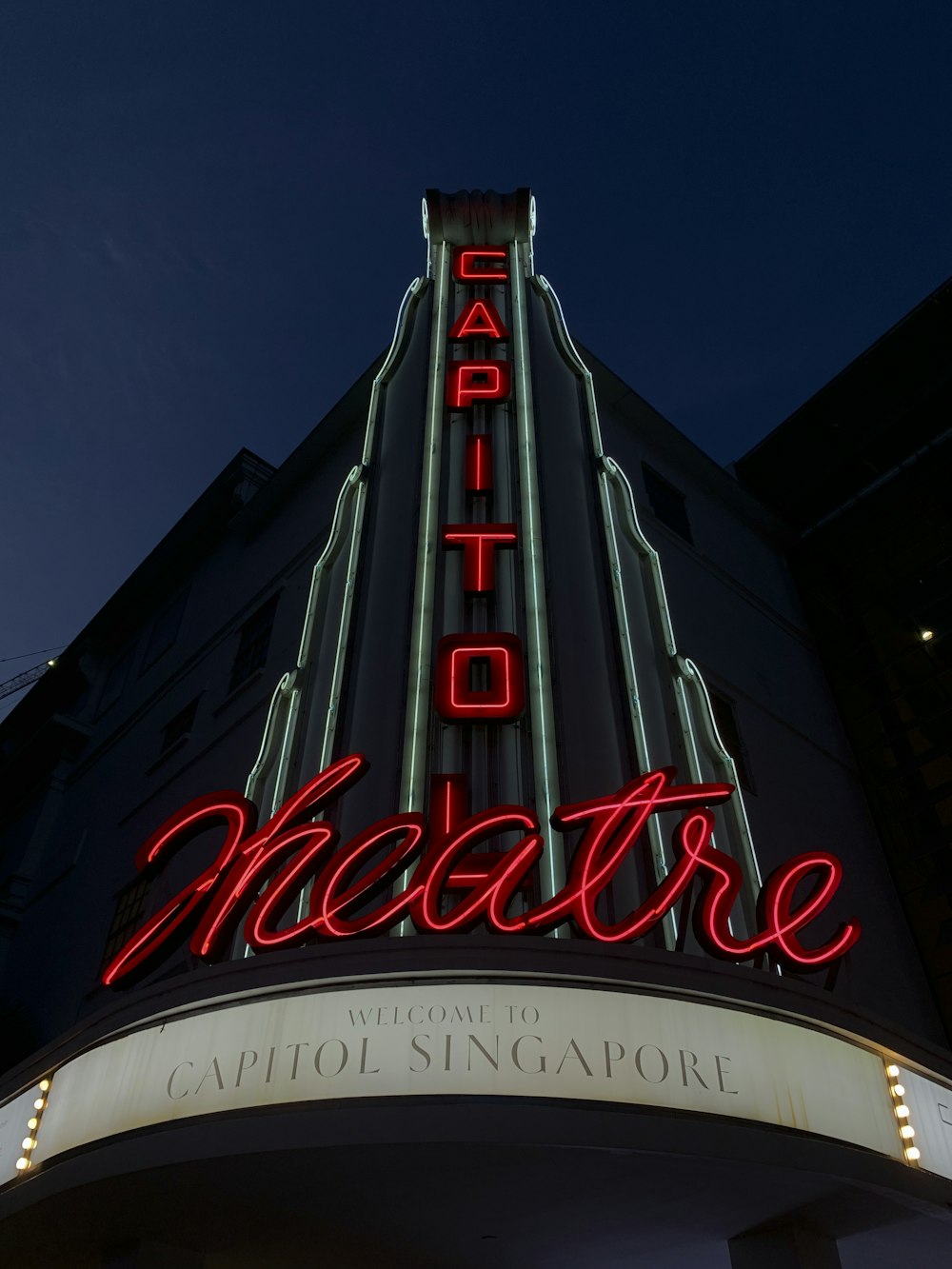 a building with a neon sign that says theatre