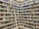 A library with rows of bookshelves filled with a variety of books organized by genre and author. A movable ladder provides access to books on higher shelves. The well-lit space has a clean and organized appearance.