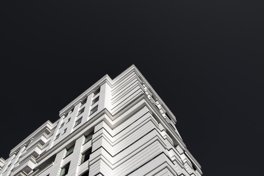 a tall white building with a black sky in the background