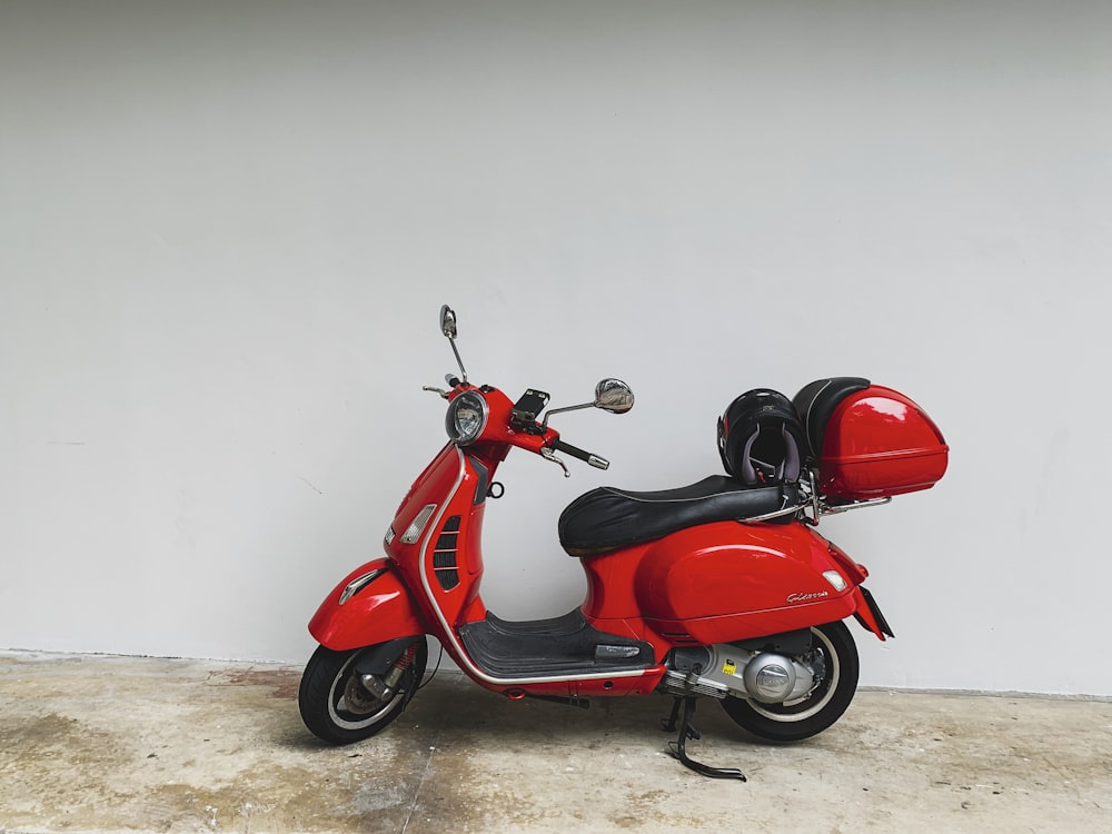 a red scooter parked in front of a white wall